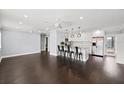 Open concept living space with modern lighting, dark hardwood floors, and a seamless flow into the kitchen at 3906 W Rogers Ave, Tampa, FL 33611