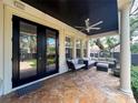 Relaxing covered patio with comfortable seating and travertine tile flooring overlooking the backyard at 4313 W Vasconia St, Tampa, FL 33629