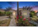 Charming single-story home at dusk featuring a well-manicured lawn and vibrant bougainvillea bushes at 4514 Arizona Sun Ct, Valrico, FL 33594