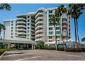 The exterior view of the condo shows a grand entrance, convenient parking, and palm trees at 1 Seaside Ln # 302, Belleair, FL 33756