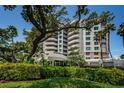 Exterior view of condo building with a lush green landscape with trees and bushes surrounding the building at 1 Seaside Ln # 302, Belleair, FL 33756