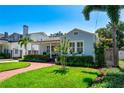 Charming blue home boasts lush landscaping, a brick walkway, and an inviting front porch with seating at 115 S Beverly Ave, Tampa, FL 33609
