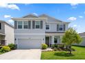Two-story home with a two-car garage, gray siding, and well-kept landscaping with stone accents at 13919 Wineberry Dr, Dade City, FL 33525