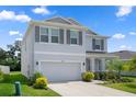 Light gray two-story home with a two-car garage, stone accents, and landscaped front yard at 13919 Wineberry Dr, Dade City, FL 33525