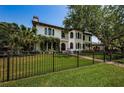 Beautiful home with black fencing, lush green lawn, and mature trees offering shade at 147 Bay Point Ne Dr, St Petersburg, FL 33704