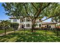 Elegant home with a black fence, manicured lawn, mature trees, and lush landscaping at 147 Bay Point Ne Dr, St Petersburg, FL 33704