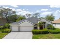 A charming home with a manicured lawn, a two-car garage, and a welcoming red front door at 1852 Longview Ln, Tarpon Springs, FL 34689