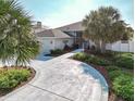 Circular driveway leading to a well-maintained home with lush landscaping and mature palm trees at 2801 Gulf Blvd, Belleair Beach, FL 33786