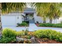 Charming home featuring a colorful front door, a well-manicured lawn, and mature palm trees at 2801 Gulf Blvd, Belleair Beach, FL 33786