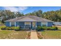 Charming blue home featuring a manicured lawn, tidy flower beds, and an inviting front porch at 3147 Sydney Dover Rd, Dover, FL 33527