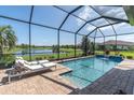 Screened-in pool features brick surround, waterfall feature, and tranquil lake views at 3167 Forsythia Dr, Odessa, FL 33556