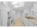 Bright kitchen featuring white cabinets, tile floors, and modern appliances for a clean aesthetic at 7330 Abalone Dr, Port Richey, FL 34668