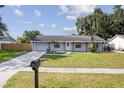 Inviting home exterior with a well-maintained lawn, long driveway, and classic architectural details under a blue sky at 9053 Hickory Cir, Tampa, FL 33615