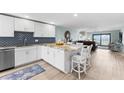 Open-concept kitchen featuring modern white cabinetry, stainless steel appliances, and a breakfast bar at 12525 3Rd E St # 303, Treasure Island, FL 33706