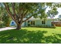 Inviting single-story home showcasing lush green lawn, mature trees, and manicured landscaping at 1281 Robin Hood Ln, Dunedin, FL 34698