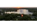Stunning aerial view of lakefront property at sunset, nestled among trees with peaceful water at 14449 Wadsworth Dr, Odessa, FL 33556