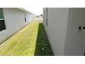 Narrow grassy side yard between two houses, leading towards a view of a pond at 16728 Kingman Reef St, Wimauma, FL 33598