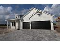 Modern two-story home featuring black garage doors and a paved driveway at 18033 Foxtail Loop, Venice, FL 34293