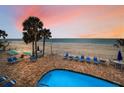 View of the pool with beach chairs and umbrellas with the beach and ocean in the background at 24 Gulf Blvd # 1C, Indian Rocks Beach, FL 33785