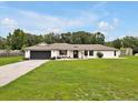 Inviting single-story home showcasing a dark garage door and a beautifully landscaped front yard with green grass at 25555 Oaks Blvd, Land O Lakes, FL 34639
