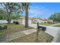 Street view of the property with a two-car garage, mature trees, and a mailbox at 3021 Jarvis St, Holiday, FL 34690