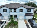 Aerial view of a two-story townhome showcases manicured landscaping and private garages at 30729 Veridian Way, Wesley Chapel, FL 33543
