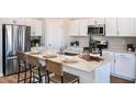 Bright kitchen featuring an island, white cabinets, stainless steel appliances, and seating for four at 36953 Sagemoor Dr, Zephyrhills, FL 33541