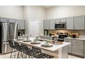 Modern kitchen features stainless steel appliances, stylish gray cabinets, and a large island with barstool seating at 36995 Sagemoor Dr, Zephyrhills, FL 33541