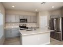 Modern kitchen features stainless steel appliances, gray cabinets, and a center island at 37009 Sagemoor Dr, Zephyrhills, FL 33541