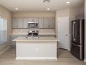 Modern kitchen features stainless steel appliances, gray cabinets, and a center island at 37009 Sagemoor Dr, Zephyrhills, FL 33541