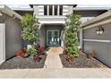 Front entrance of a gray home with a brick walkway, a pair of double front doors, and manicured landscaping at 5813 Bent Grass Dr, Valrico, FL 33596