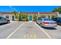 Inviting townhome features assigned parking spaces, tropical landscaping, and a delightful turquoise front door at 9142 Oakwood Ln, Seminole, FL 33776
