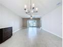 Expansive living room with light tile flooring, chandelier, and sliding glass doors at 10347 Heron Hideaway Loop, Land O Lakes, FL 34638