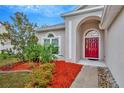Inviting front entrance with a striking red door, complemented by colorful landscaping and manicured lawn at 11123 Silver Dancer Dr, Riverview, FL 33579