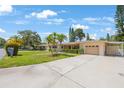 Exterior view featuring a well-manicured lawn, mature palms, and a single car garage at 1305 Marion S Dr, St Petersburg, FL 33707