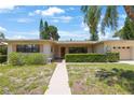 Charming single-story home with a well-manicured lawn, lush shrubbery, and a welcoming walkway leading to the front door at 1305 Marion S Dr, St Petersburg, FL 33707