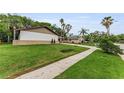 View of a single-story house, green lawn with a sidewalk running adjacent to the property at 1558 Cottonwood Ter, Dunedin, FL 34698