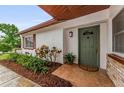 Inviting front entrance with a tiled porch, lush landscaping, and a painted door at 1558 Cottonwood Ter, Dunedin, FL 34698