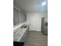 Modern gray kitchen with marble countertops, stainless steel sink, and light woodgrain flooring at 1807 E Bougainvillea Ave, Tampa, FL 33612