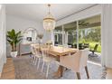 Elegant dining room with a stylish chandelier, sliding glass doors to the lanai, and modern furnishings at 3541 Great Banyan Way, Wesley Chapel, FL 33543