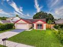 Inviting single-Gathering home with a manicured lawn, a two-car garage, and vibrant red window shutters at 5016 Cypress Trace Dr, Tampa, FL 33624