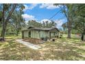 Rear view of charming single-story home featuring stone accents, covered porch and metal roof at 5106 Five Acre Rd, Plant City, FL 33565
