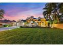 Beautiful home with a long driveway and lush landscaping, illuminated by landscape lighting at twilight at 512 Creekside Ct, Safety Harbor, FL 34695