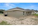 Rear exterior featuring a covered patio, neutral color palette, and an expansive yard at 5441 Chestnut Ridge Rd, Dade City, FL 33523