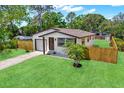 Charming home featuring lush green lawn, cute palm tree, and a partially fenced yard at 6220 Pershing Ne St, St Petersburg, FL 33702