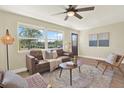 Cozy living room with leather sofa, ceiling fan, and natural light from the large windows at 6220 Pershing Ne St, St Petersburg, FL 33702