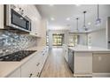 Bright kitchen featuring stainless steel appliances, white cabinets, a patterned backsplash, and an island at 7276 Notched Pine Bnd, Wesley Chapel, FL 33545
