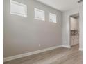 Bright, empty room with light gray walls, wood-look tile floors, and 3 windows facing front at 7276 Notched Pine Bnd, Wesley Chapel, FL 33545