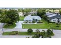 Aerial view of single-story blue home on a manicured lawn with palm trees and a long driveway at 8679 Burning Tree Cir, Seminole, FL 33777