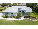 Beautiful single-story home with blue exterior, arched windows, manicured lawn and palm trees at 8679 Burning Tree Cir, Seminole, FL 33777